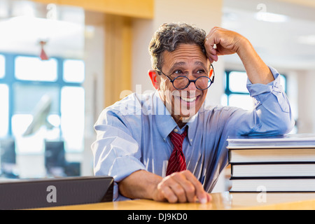 Ältere Mann lächelnd in Bibliothek Stockfoto