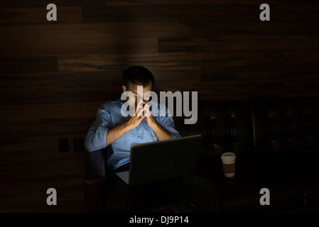 Geschäftsmann mit Laptop auf dem Sofa in der Nacht Stockfoto