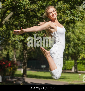 Seitenansicht der junge Fit Frau verbreiten ihre Arme springen Stockfoto