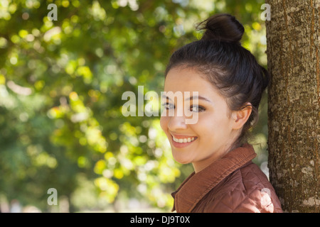 Schöne junge Frau posiert an einen Baum gelehnt Stockfoto