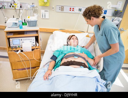 Krankenschwester mit schwangeren Patienten im Krankenhausbett liegend zu kommunizieren Stockfoto