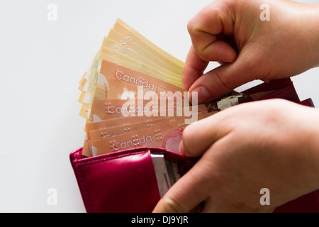 Menschliche Hand ziehen Geld aus der Brieftasche kanadischen Brieftasche mit kanadischen Geld. Stockfoto