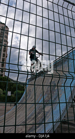 Ein Skateboarder auf einer Rampe mit einem Hochhaus hinter ihm Stockfoto