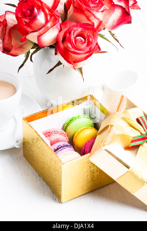 Makronen in Geschenk-Box und Rosen in vase Stockfoto