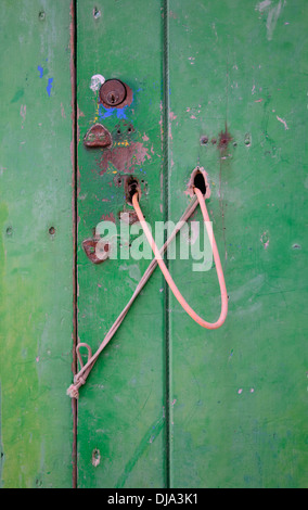 Grüne Tür mit rostigen Schlösser und rosa Streicher-Arrangement. Stockfoto