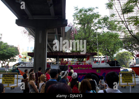 Leute warten vor Amphibienfahrzeug The Duck Tour zur Kreuzfahrt in Singapur, über Brücke rechts oben. Stockfoto