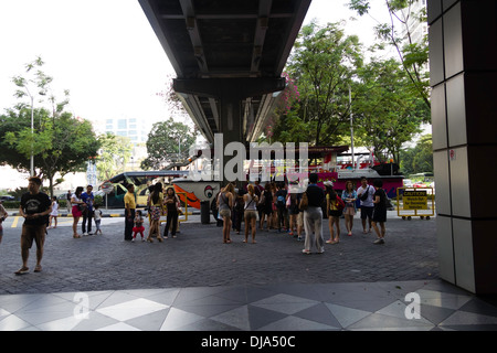 Leute warten vor Amphibienfahrzeug The Duck Tour zur Kreuzfahrt in Singapur, über Brücke rechts oben. Stockfoto