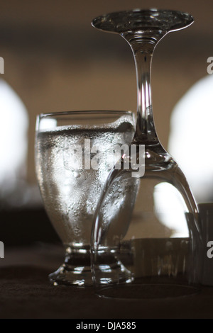 Ein Glas Wasser neben einem leeren umgedrehten Glas Wein. Stockfoto