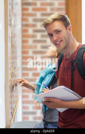 Fröhliche Student auf der Suche etwas am schwarzen Brett Stockfoto