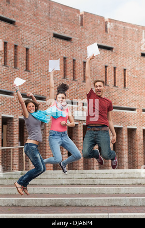 Glückliche Schüler springen in der Luft halten Prüfung Stockfoto