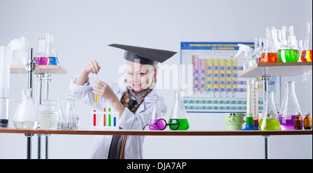 Entzückende kleine Chemiker posiert im Labor mit Fläschchen Stockfoto