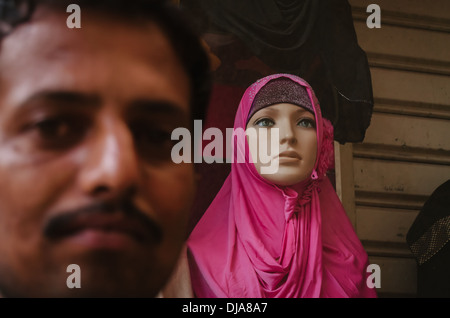 Ein Mann posiert vor einer Schaufensterpuppe einen rosa Hijab zu tragen, in den Straßen von Deira. Dubai, Vereinigte Arabische Emirate. Stockfoto