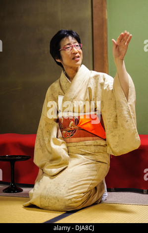 Applying Dame im Kimono auf traditionelle Tatami-Matten in einem Teehaus kniend, wie sie Belehrung über die Teezeremonie gibt. Stockfoto