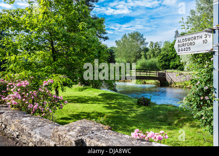 Blick über den Fluss Coln in Bibury mit einem Wegweiser nach anderen Cotswold-Städte und Dörfer und der Forellenzucht. Stockfoto