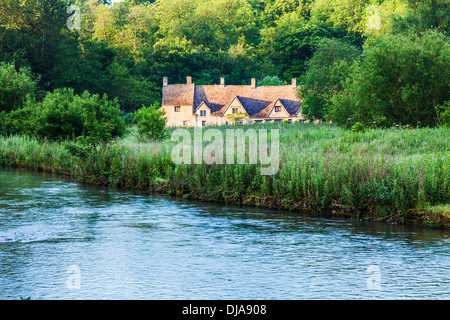 Blick über den Fluss Coln und Rack Isle Wasser Wiese zu den berühmten Arlington Row Cottages in Cotswold Dorf von Bibury. Stockfoto