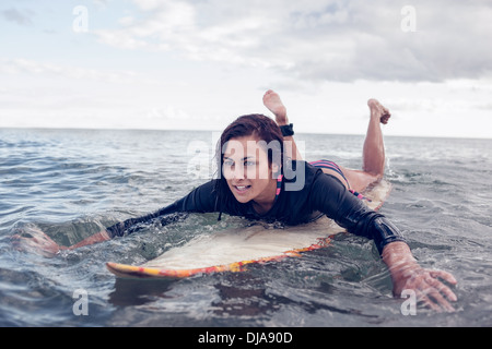 Junge Frau über Surfbrett im Wasser schwimmen Stockfoto