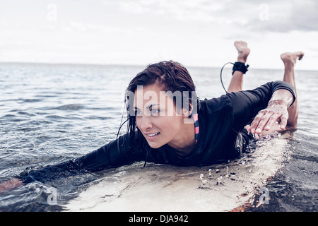 Junge Frau über Surfbrett im Wasser schwimmen Stockfoto