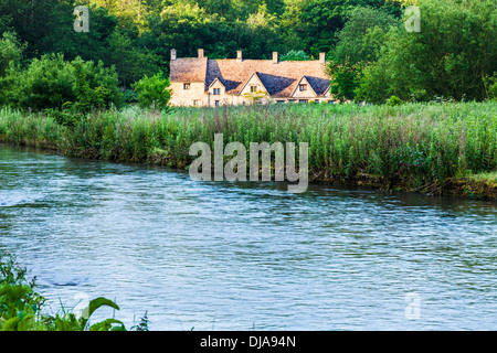 Blick über den Fluss Coln und Rack Isle Wasser Wiese zu den berühmten Arlington Row Cottages in Cotswold Dorf von Bibury. Stockfoto