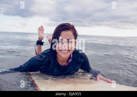 Porträt einer Frau, die über Surfbrett im Wasser schwimmen Stockfoto