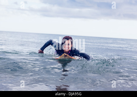 Lächelnde Frau über Surfbrett im Wasser schwimmen Stockfoto