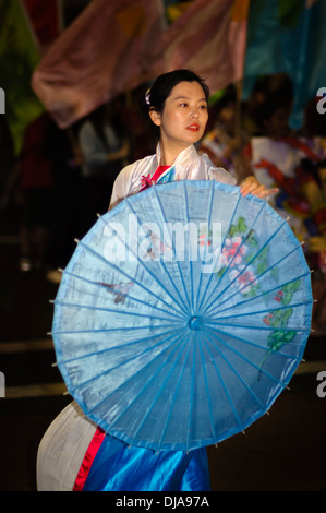 Frau tanzt mit einem ziemlich gemusterter Regenschirm in einer chinesischen Neujahr parade Stockfoto