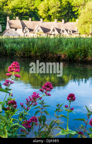 Blick über den Fluss Coln und Rack Isle Wasser Wiese zu den berühmten Arlington Row Cottages in Cotswold Dorf von Bibury. Stockfoto