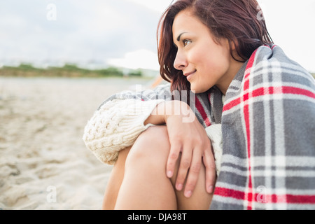 Seitenansicht der Frau bedeckt mit Decke am Strand Stockfoto