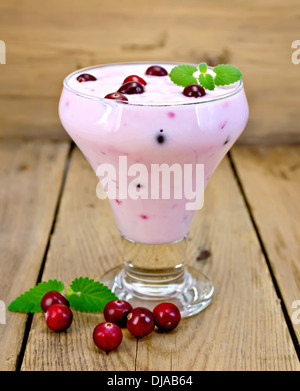 Dicken Joghurt im Glas mit Preiselbeeren, Mint auf Holzbrettern Hintergrund Stockfoto