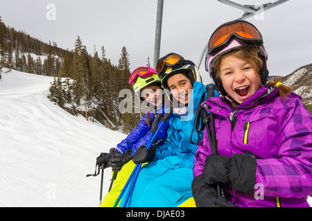 Mädchen reiten Skilift auf verschneiten Hang Stockfoto