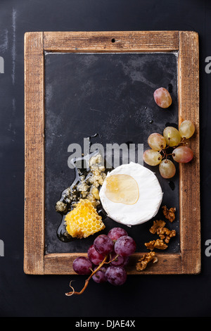 Käse mit Honig, Nüssen und Trauben an Vintage Schiefer Tafel Stockfoto