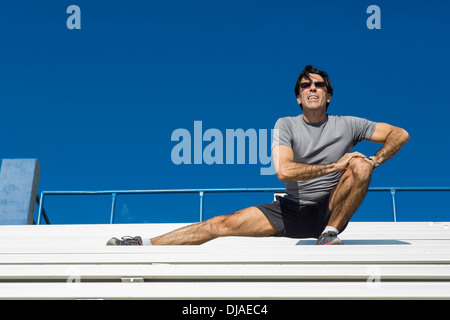 Hispanic Athleten Dehnung auf Tribüne Stockfoto