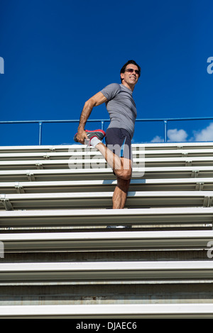 Hispanic Athleten Dehnung auf Tribüne Stockfoto