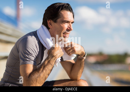 Hispanic Mann ruht mit Handtuch um den Hals Stockfoto