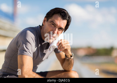 Hispanic Mann ruht mit Handtuch um den Hals Stockfoto