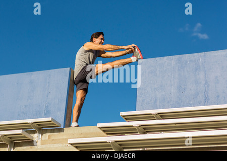 Hispanic Athleten Dehnung auf Tribüne Stockfoto