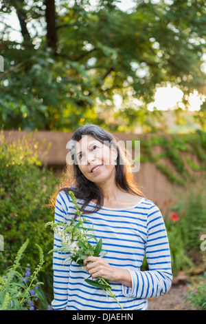 Hispanic Frau mit Blumen im Garten Stockfoto