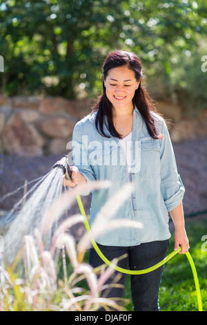 Gemischte Rassen Frau Bewässerung von Pflanzen im Garten Stockfoto