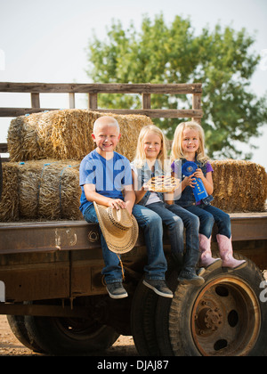 Kaukasische Kinder sitzen auf LKW auf Bauernhof Stockfoto