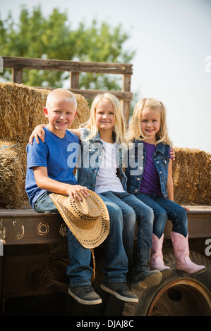 Kaukasische Kinder sitzen auf LKW auf Bauernhof Stockfoto