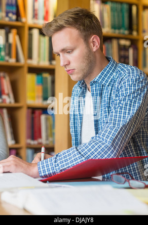Junge männliche Schüler schreiben von Notizen an Bibliothek Schreibtisch Stockfoto