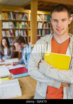 Männliche Schüler mit anderen im Hintergrund in Bibliothek Stockfoto