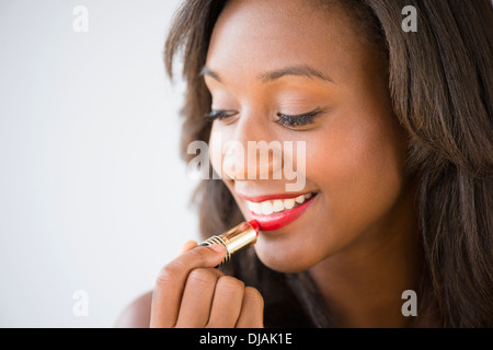 Schwarze Frau Auftragen von Lippenstift Stockfoto
