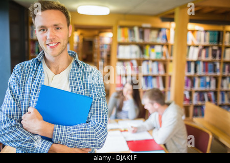 Männliche Schüler mit anderen im Hintergrund in Bibliothek Stockfoto