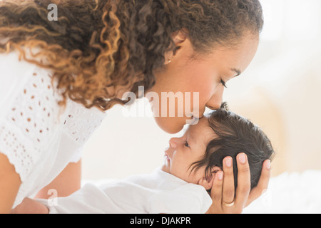 Hispanische Mutter Babys Stirn küssen Stockfoto
