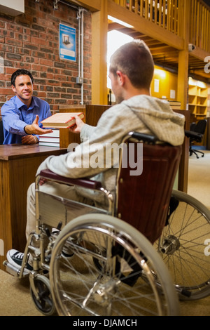 Student im Rollstuhl an der Bibliothek-Theke Stockfoto