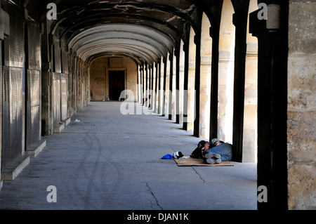 Paris, Frankreich. Place des Vosges. Mann schläft unter dem Bogengang Stockfoto