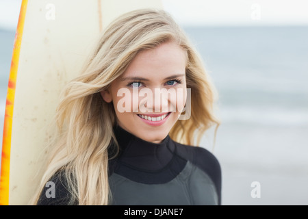 Porträt einer lächelnden, schönen Frau mit Surfbrett Stockfoto