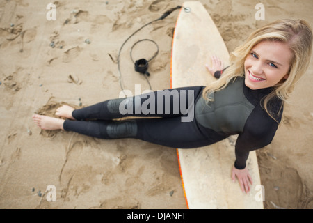 Obenliegende Porträt von Blond im Neoprenanzug mit Surfbrett am Strand Stockfoto