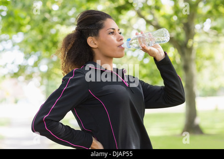 Müde gesunde Frau Trinkwasser im park Stockfoto