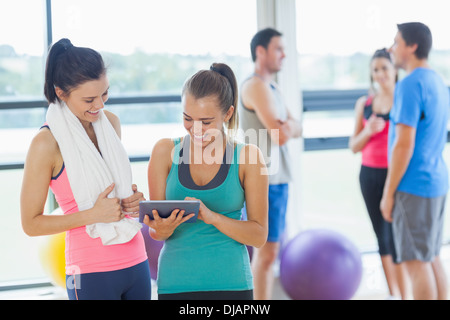 Passen Sie Frauen, die an digitalen Tisch mit Freunden im Chat im Hintergrund Stockfoto